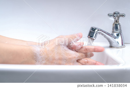 Woman washing hand with soap foam and tap water in bathroom. Hand clean under faucet on sink for personal hygiene to prevent flu and coronavirus. Good procedure of hand wash to kill bacteria, virus. Woman washing hand with soap foam and tap water in bathroom. Hand clean under faucet on sink for personal hygiene to prevent flu and coronavirus. Good procedure of hand wash to kill bacteria, virus. 141838034