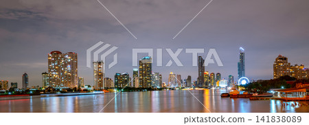 Panoramic Bangkok skyline at night along Chao Phraya River, Thailand, illuminated skyscrapers, modern architecture and urban waterfront cityscape. Financial district and waterfront architecture. Panoramic Bangkok skyline at night along Chao Phraya River, Thailand, illuminated skyscrapers, modern architecture and urban waterfront cityscape. Financial district and waterfront architecture. 141838089