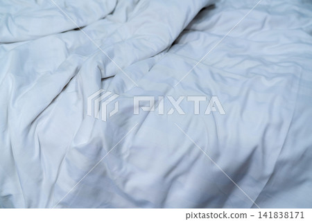 Messy white bedding with rumpled duvet and clean cotton sheets. Bedroom background for sleep quality, relaxation, hospitality, interior design, and wellness theme. Hotel, hospitality, sleep, wellness. 141838171