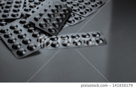 Silver aluminum blister packs with copy space on gray background for pharmaceutical industry. Hospital medicine supplies, pharmacy products, prescription drug packaging and healthcare retail market. Silver aluminum blister packs with copy space on gray background for pharmaceutical industry. Hospital medicine supplies, pharmacy products, prescription drug packaging and healthcare retail market. 141838179