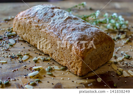 Close-up view of rustic artisan bread loaf with flour-dusted crust on wooden table. Homemade bakery bread and organic food concept. Close-up view of rustic artisan bread loaf with flour-dusted crust on wooden table. Homemade bakery bread and organic food concept. 141838249
