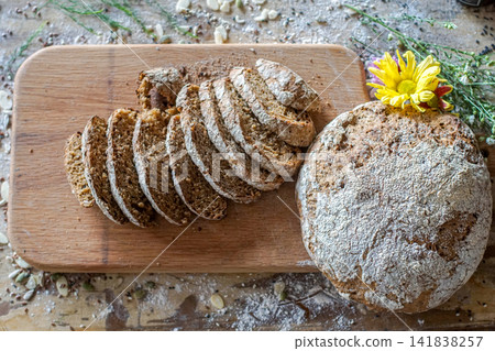 Rustic artisan bread loaf sliced on wooden board photographed from above. Homemade bakery food concept. Rustic artisan bread loaf sliced on wooden board photographed from above. Homemade bakery food concept. 141838257