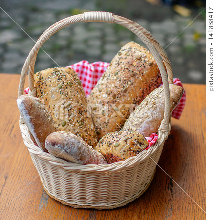 Assorted artisan bread rolls and seeded baguettes in rustic wicker basket. Clean food photography with natural light highlighting texture and bakery freshness. Assorted artisan bread rolls and seeded baguettes in rustic wicker basket. Clean food photography with natural light highlighting texture and bakery freshness. 141838417