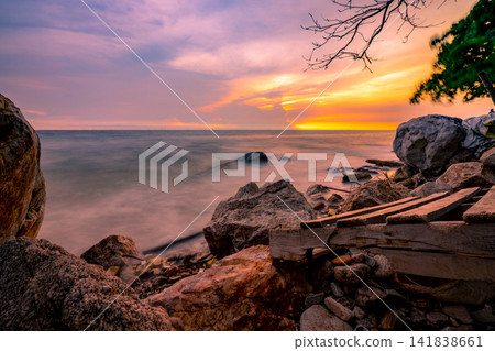 Rock beach with blue and golden sunset sky. Skyline between sea water and sky in the evening. Calm ocean with soft wave. Summer travel at tropical sea and stone beach. Beauty in nature. Seascape. Rock beach with blue and golden sunset sky. Skyline between sea water and sky in the evening. Calm ocean with soft wave. Summer travel at tropical sea and stone beach. Beauty in nature. Seascape. 141838661