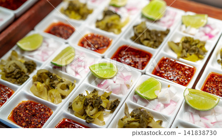 Lunch buffet at the event in a restaurant. Catering food. Banquet service. Thai food buffet catering concept. White plate set of onions chopped, lemon sliced, pickled cabbage, and chilli powder fried. Lunch buffet at the event in a restaurant. Catering food. Banquet service. Thai food buffet catering concept. White plate set of onions chopped, lemon sliced, pickled cabbage, and chilli powder fried. 141838730