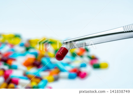 Forceps pick red-white capsule from group of capsule pills. Drugs choose. Drug selection. QA and QC in pharmaceutical factory concept. Drugs of choice. Capsule pill in laboratory for quality test. Forceps pick red-white capsule from group of capsule pills. Drugs choose. Drug selection. QA and QC in pharmaceutical factory concept. Drugs of choice. Capsule pill in laboratory for quality test. 141838749