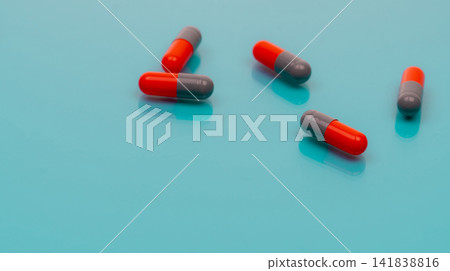 Gray-orange antibiotic capsules pill spread on blue background. Pharmacy banner. Prescription drug. Antibiotic drug resistance. Pharmaceutical industry. Healthcare and medicine. Antimicrobial drugs. Gray-orange antibiotic capsules pill spread on blue background. Pharmacy banner. Prescription drug. Antibiotic drug resistance. Pharmaceutical industry. Healthcare and medicine. Antimicrobial drugs. 141838816
