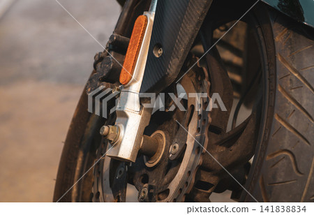 Closeup disc brake of motorcycle. Motorbike accessory. Aluminum alloy wheel of dirty motorcycle. Mag wheels of old motorbike. Performance wheel and tire of motorcycle. Chrome disc brake and abs. Closeup disc brake of motorcycle. Motorbike accessory. Aluminum alloy wheel of dirty motorcycle. Mag wheels of old motorbike. Performance wheel and tire of motorcycle. Chrome disc brake and abs. 141838834