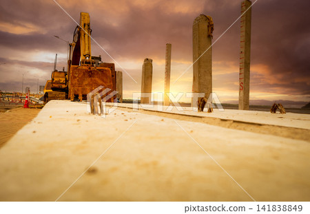 Selective focus on bucket of old backhoe. Digger parked at construction site. Bulldozer near concrete pole. Earth moving machine. Yellow digger with bucket. Earth moving machine. Excavation vehicle. Selective focus on bucket of old backhoe. Digger parked at construction site. Bulldozer near concrete pole. Earth moving machine. Yellow digger with bucket. Earth moving machine. Excavation vehicle. 141838849