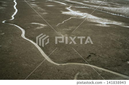 Landscape of coastal mud. Loneliness. Beach on tide. Water canal with natural pattern. Grey clay. Coastal ecosystems. Delta estuary. Landscape of coastal mud. Loneliness. Beach on tide. Water canal with natural pattern. Grey clay. Coastal ecosystems. Delta estuary. 141838943