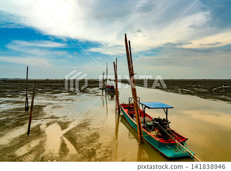 Fisherman's boat parked at coastal mud flat at tide. Landscape of sea and beautiful blue sky and white clouds. Mud beach. Fisherman's boat parked at coastal mud flat at tide. Landscape of sea and beautiful blue sky and white clouds. Mud beach. 141838946
