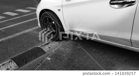A white car drove over a speed bump. A white car drove over a speed bump. 141839257