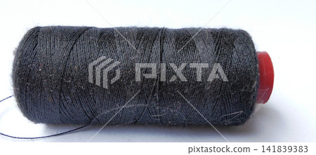 A spool of black sewing thread against a plain background. A spool of black sewing thread against a plain background. 141839383