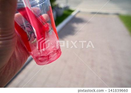 Hand Holding Pink Bubble Tea with Tapioca Pearls Outdoors Hand Holding Pink Bubble Tea with Tapioca Pearls Outdoors 141839660