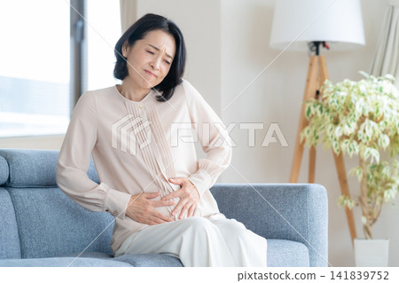 一位中年婦女在客廳感到身體不適。 141839752