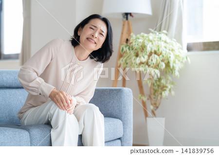 A middle-aged woman who is feeling unwell in the living room A middle-aged woman who is feeling unwell in the living room 141839756