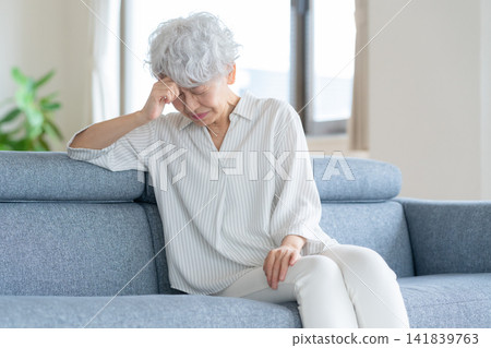 A senior woman who is feeling unwell in the living room A senior woman who is feeling unwell in the living room 141839763