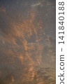 Dramatic orange sunset sky covered with delicate cirrus clouds, creating a warm atmospheric scene with vibrant colors and soft natural light. 141840188