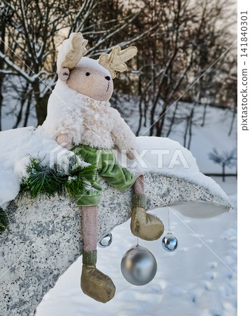 A natural Christmas tree stands decorated with colorful ornaments and snow. It is located in a park setting during New Year celebrations A natural Christmas tree stands decorated with colorful ornaments and snow. It is located in a park setting during New Year celebrations 141840301