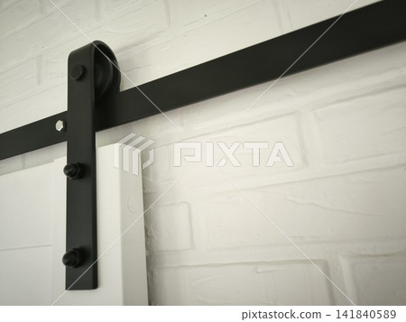 Black barn door mechanism and white sliding door on white wall Black barn door mechanism and white sliding door on white wall 141840589