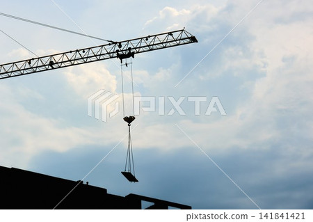 Silhouette of Industrial Tower Crane Lifting Slab against Cloudy Sky Silhouette of Industrial Tower Crane Lifting Slab against Cloudy Sky 141841421