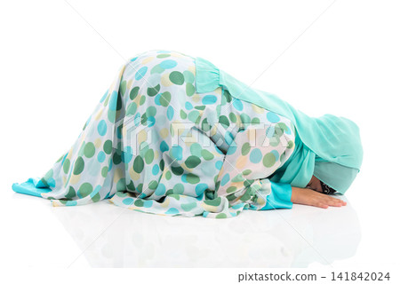 Side view horizontal portrait of cute young Asian Muslim girl performing Sujud prostration isolated on white background. Side view horizontal portrait of cute young Asian Muslim girl performing Sujud prostration isolated on white background. 141842024