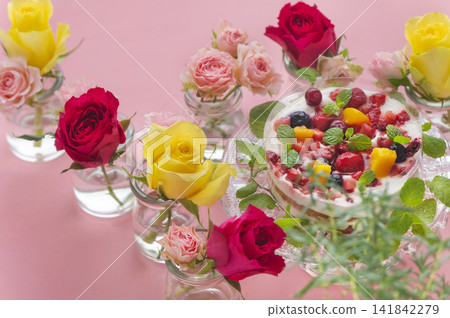 A berry and fruit cake and vibrant roses stand out against a pink background. A berry and fruit cake and vibrant roses stand out against a pink background. 141842279