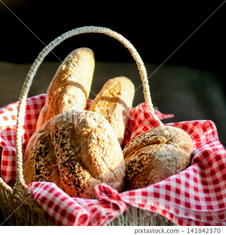 Rustic Artisan Bread Loaves with Sesame Seeds in Woven Basket and Red Gingham Cloth Rustic Artisan Bread Loaves with Sesame Seeds in Woven Basket and Red Gingham Cloth 141842370