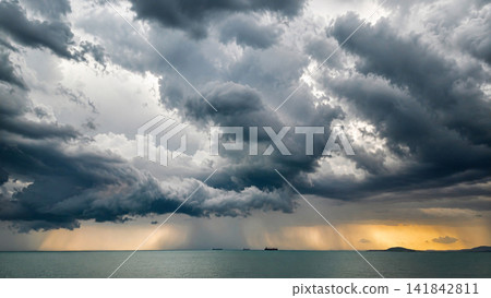 Dramatic Storm Clouds Over Sea with Rain Showers at Sunset Dramatic Storm Clouds Over Sea with Rain Showers at Sunset 141842811
