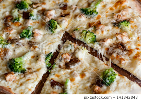 A close-up of chicken and broccoli pizza with melted cheese and sliced sections. A close-up of chicken and broccoli pizza with melted cheese and sliced sections. 141842848