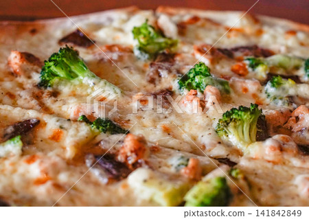 Detailed close-up of a pizza topped with chicken, broccoli, and melted cheese. Suitable for menus, ads, recipe uses, restaurant visuals, and food-related design materials. Detailed close-up of a pizza topped with chicken, broccoli, and melted cheese. Suitable for menus, ads, recipe uses, restaurant visuals, and food-related design materials. 141842849