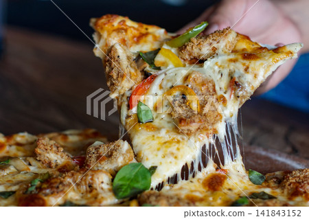 Hand Holding Crispy Chicken Pizza Slice with Melting Cheese 141843152