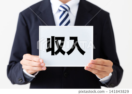 一位身穿西裝的年輕商人手持白板，上面顯示著他的收入。 141843829