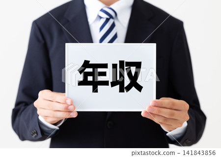 A young businessman in a business suit holding a whiteboard displaying annual incomes. A young businessman in a business suit holding a whiteboard displaying annual incomes. 141843856