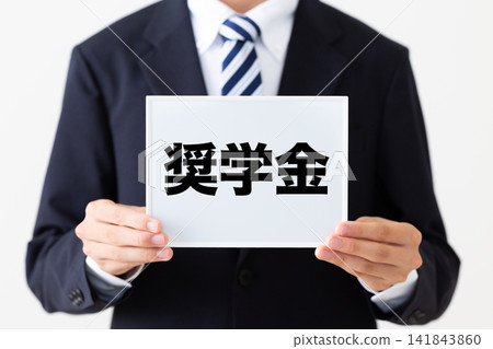 A young businessman in a business suit holding a whiteboard with scholarship information. A young businessman in a business suit holding a whiteboard with scholarship information. 141843860