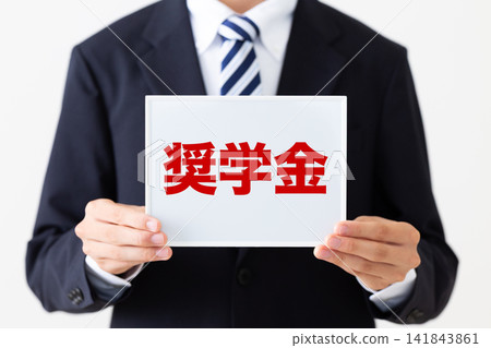 身穿西裝的年輕商人,手持一塊寫有獎學金訊息的白板。 身穿西裝的年輕商人,手持一塊寫有獎學金訊息的白板。 141843861