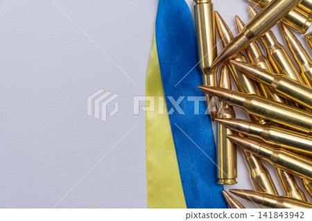 Rifle cartridges arranged beside blue and yellow ribbon on white Rifle cartridges arranged beside blue and yellow ribbon on white 141843942