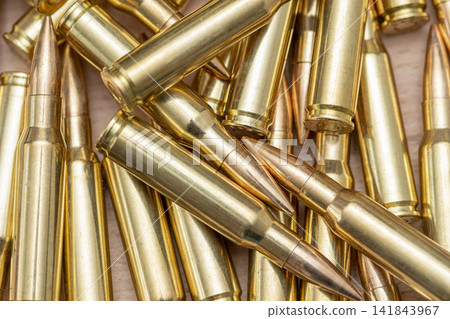 Closeup pile of brass rifle cartridges with pointed copper bullets Closeup pile of brass rifle cartridges with pointed copper bullets 141843967