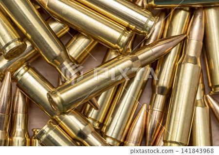 Closeup view of scattered brass rifle cartridges with pointed copper bullets Closeup view of scattered brass rifle cartridges with pointed copper bullets 141843968