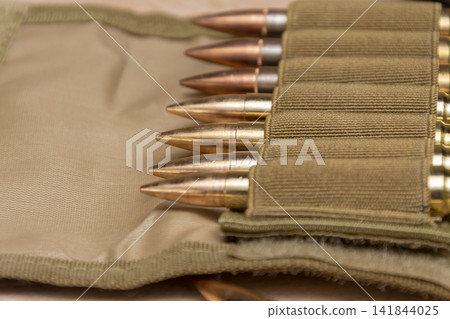 Close up of rifle cartridges arranged in a tan fabric holder Close up of rifle cartridges arranged in a tan fabric holder 141844025