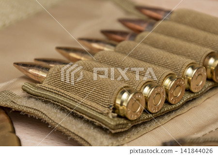Close up of rifle cartridges in a tan fabric ammunition holder Close up of rifle cartridges in a tan fabric ammunition holder 141844026