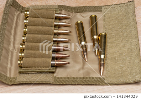 Rifle cartridges arranged in tan fabric pouch on wooden surface Rifle cartridges arranged in tan fabric pouch on wooden surface 141844029