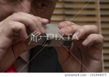 Spy photographs secret materials on a mini camera, collecting compromising material, special agent and intelligence officer , private investigator. Spy photographs secret materials on a mini camera, collecting compromising material, special agent and intelligence officer , private investigator. 141844077