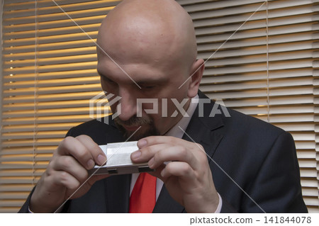 Spy photographs secret materials on a mini camera, collecting compromising material, special agent and intelligence officer , private investigator. Spy photographs secret materials on a mini camera, collecting compromising material, special agent and intelligence officer , private investigator. 141844078