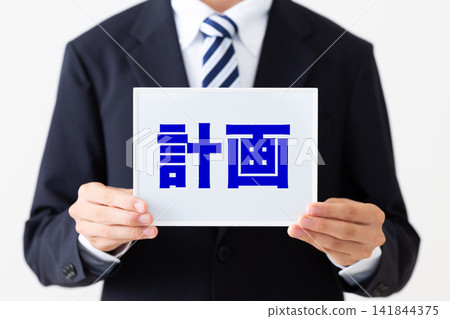 一位身穿西裝的年輕商人，手持一塊寫著計畫的白板。 141844375