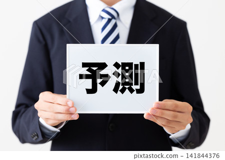 一位身穿西裝的年輕商人,手持一塊寫著預測的白板。 一位身穿西裝的年輕商人,手持一塊寫著預測的白板。 141844376