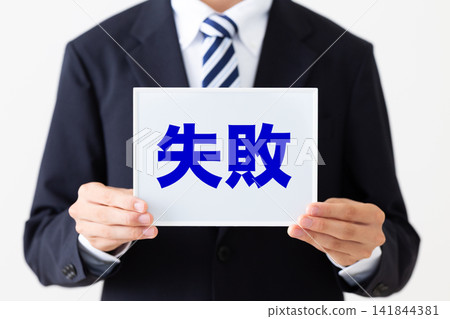 A young businessman in a business suit holding a whiteboard of failures. A young businessman in a business suit holding a whiteboard of failures. 141844381