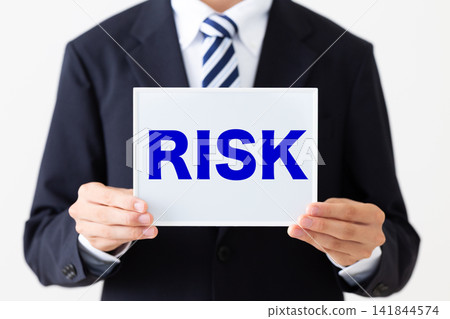 A young businessman in a business suit holding a RISK whiteboard. A young businessman in a business suit holding a RISK whiteboard. 141844574