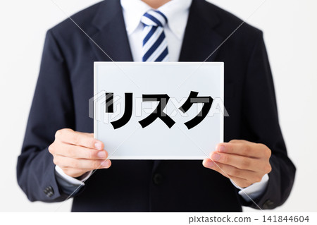 一位身穿西裝的年輕商人,手持一張寫著風險清單的白板。 一位身穿西裝的年輕商人,手持一張寫著風險清單的白板。 141844604