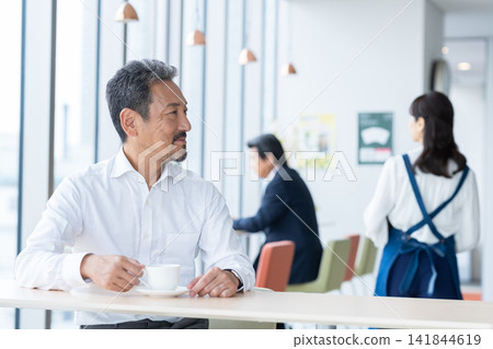 A middle-aged man relaxing in a cafe. Photo courtesy of Denpa Gakuen Educational Foundation, Tokyo Electronics College. A middle-aged man relaxing in a cafe. Photo courtesy of Denpa Gakuen Educational Foundation, Tokyo Electronics College. 141844619